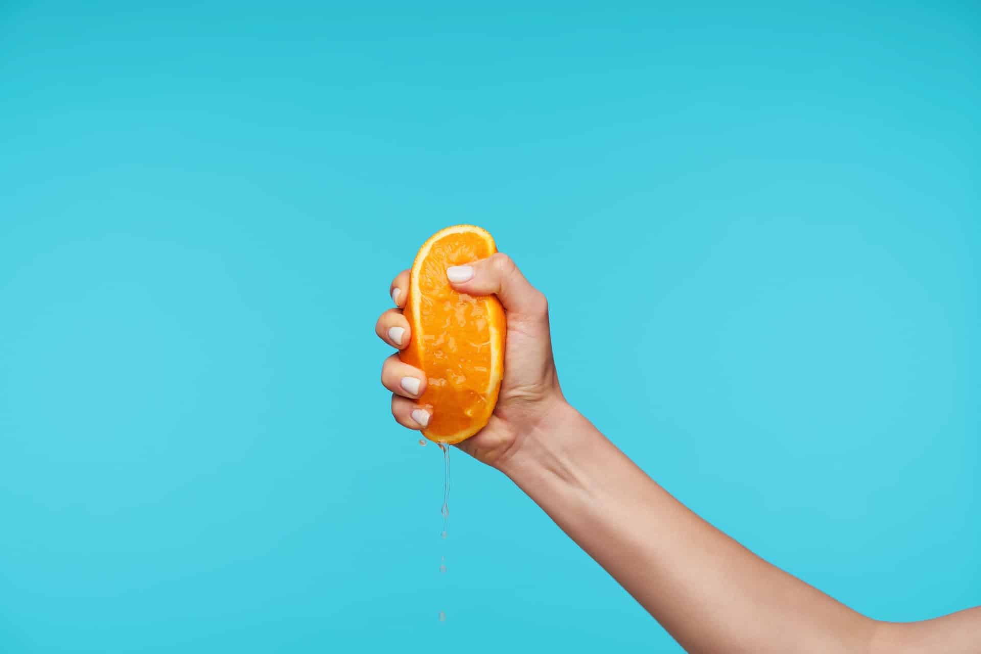 Indoor,Photo,Of,Young,Attractive,Hand,Holding,Orange,And,Clenching